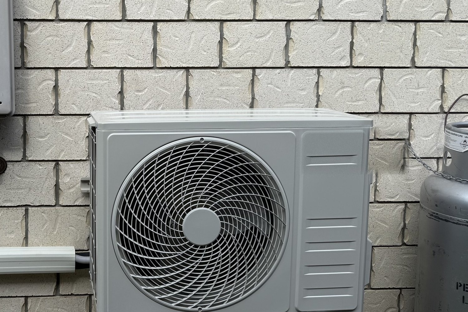 Outdoor condenser unit mounted on a brick wall